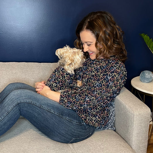 Dog Mom and her pup in matching shirts cuddling on the sofa
