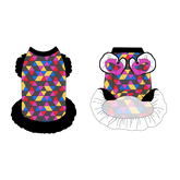 Dress with ruffle accents on the shoulders and girly ruffle skirt in a dog friendly pattern that shows a girl dog with hat and necklace, along with a mirror ball, champagne glasses, fireworks and confetti on a magenta cheetah print background. It's complete with black trim on the neck and ruffles, as well as a coordinating trim under the shoulder ruffles in magenta.