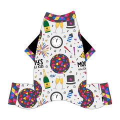 Comfy New Years Pajamas with solid black sleeves in a dog friendly pattern that shows a multi-colored New Years ball, the words Mommy's Midnight Kiss, a clock, champagne bottle and champagne toast, fireworks, confetti and more on a white background. It's complete with NYE Ball trim on the neck, sleeves and legs.