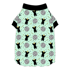 Tee shirt with flutter hem in a dog friendly pattern that shows a mirror ball, dog with a party blower and confetti on a light green background. It's complete with black trim on the neck and sleeves.
