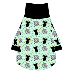 Tee shirt with turtleneck in a dog friendly pattern that shows a mirror ball, dog with a party blower and confetti on a light green background. It's complete with black trim on the neck, waist and sleeves.