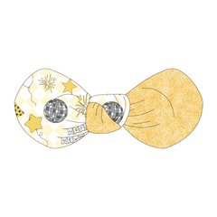 Hair bow twisted with two fabrics: one in a dog friendly pattern that shows a mirror ball, top hat, champagne toast, balloons, clock striking midnight, banner reading Happy New Year and more on a light gold and white diamond background and one side in gold sparkle.