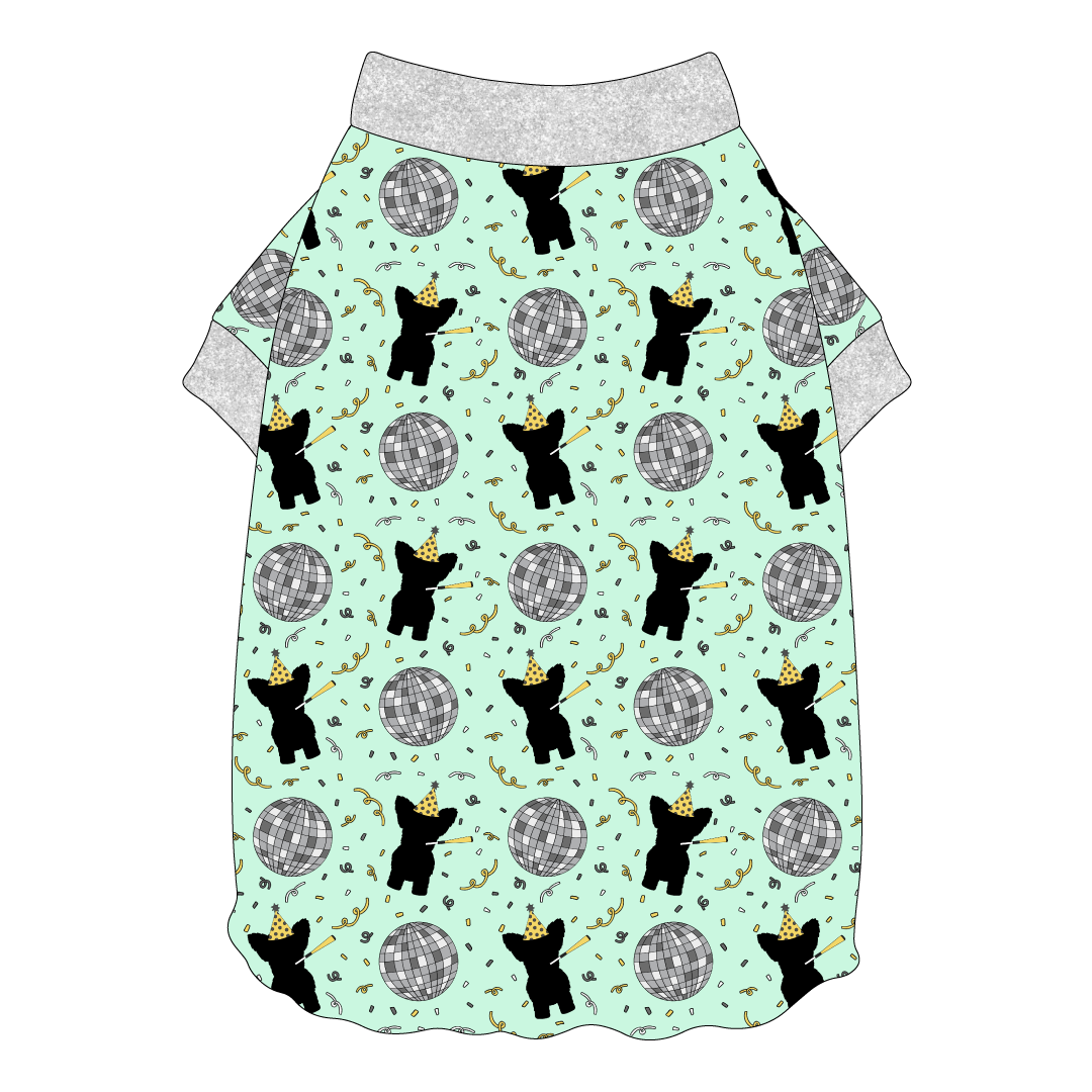 Tee shirt with flutter hem in a dog friendly pattern that shows a mirror ball, dog with a party blower and confetti on a light green background.  It's complete with silver sparkle trim on the neck and sleeves.