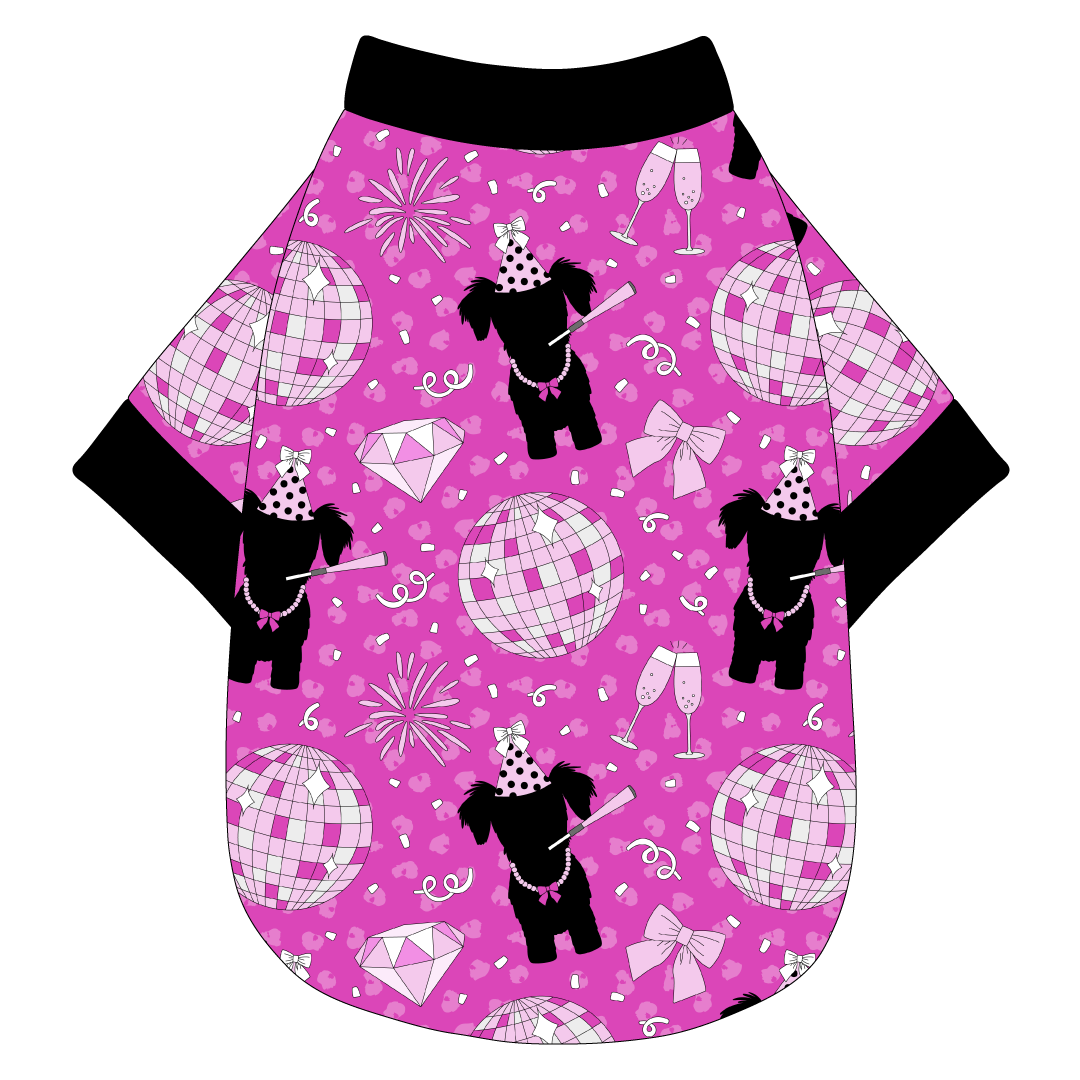 Tee shirt in a dog friendly pattern that shows a girl dog with hat and necklace, along with a mirror ball, champagne glasses, fireworks and confetti on a magenta cheetah print background. It's complete with black trim on the neck, waist and sleeves.