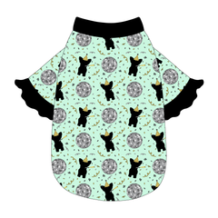 Tee style in a dog friendly pattern that shows a mirror ball, dog with a party blower and confetti on a light green background. It's complete with black ruffles on the sleeve edges. Black trim is also on the neck and waist.