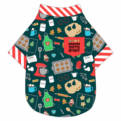 Tee shirt in a dog friendly pattern that shows cookies baking, a light green apron, recipe cards and more on a deep emerald background. It's complete with candy cane trim on the neck, waist and sleeves, as well as a red pocket that reads Baking Spirits Bright.