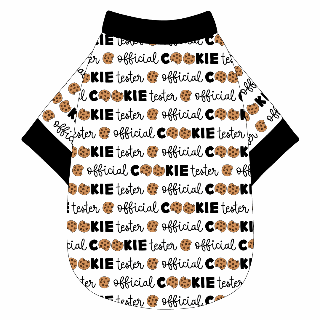 Tee shirt in a dog friendly pattern that shows the text Official Cookie Tester, using two cookies for letter “o” in cookies, on a white background. It's complete with black trim on the neck, waist and sleeves.