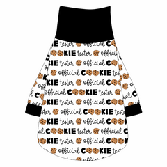 Tee shirt with turtleneck in a dog friendly pattern that shows the text Official Cookie Tester, using two cookies for letter “o” in cookies, on a white background. It's complete with black trim on the neck, waist and sleeves.