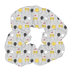 Scrunchie hair accessory in a dog friendly pattern that shows two happy champagne glasses making a toast with hearts overhead, gold star balloons and traditional balloons in white and gray on a silver sparkle background.